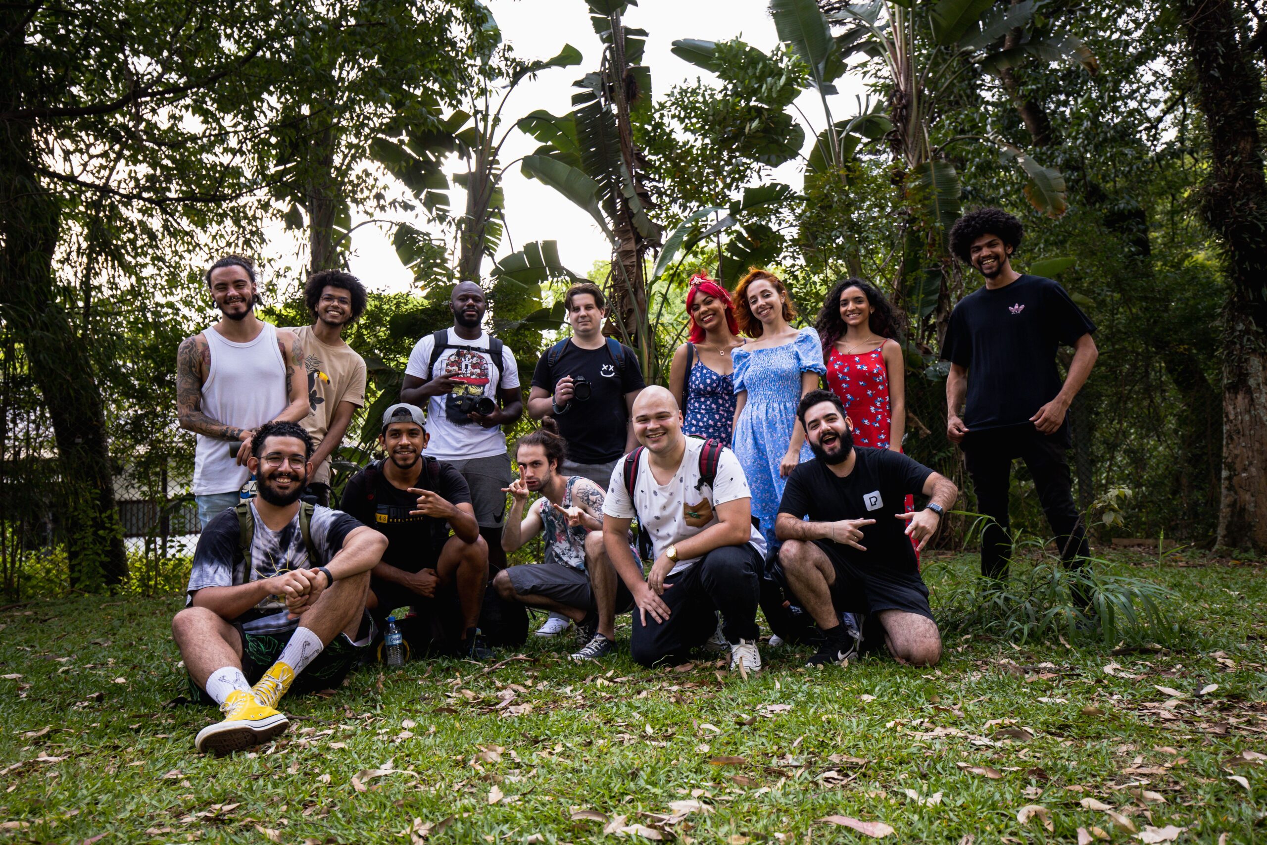 A diverse group posing happily together in a lush, outdoor setting.